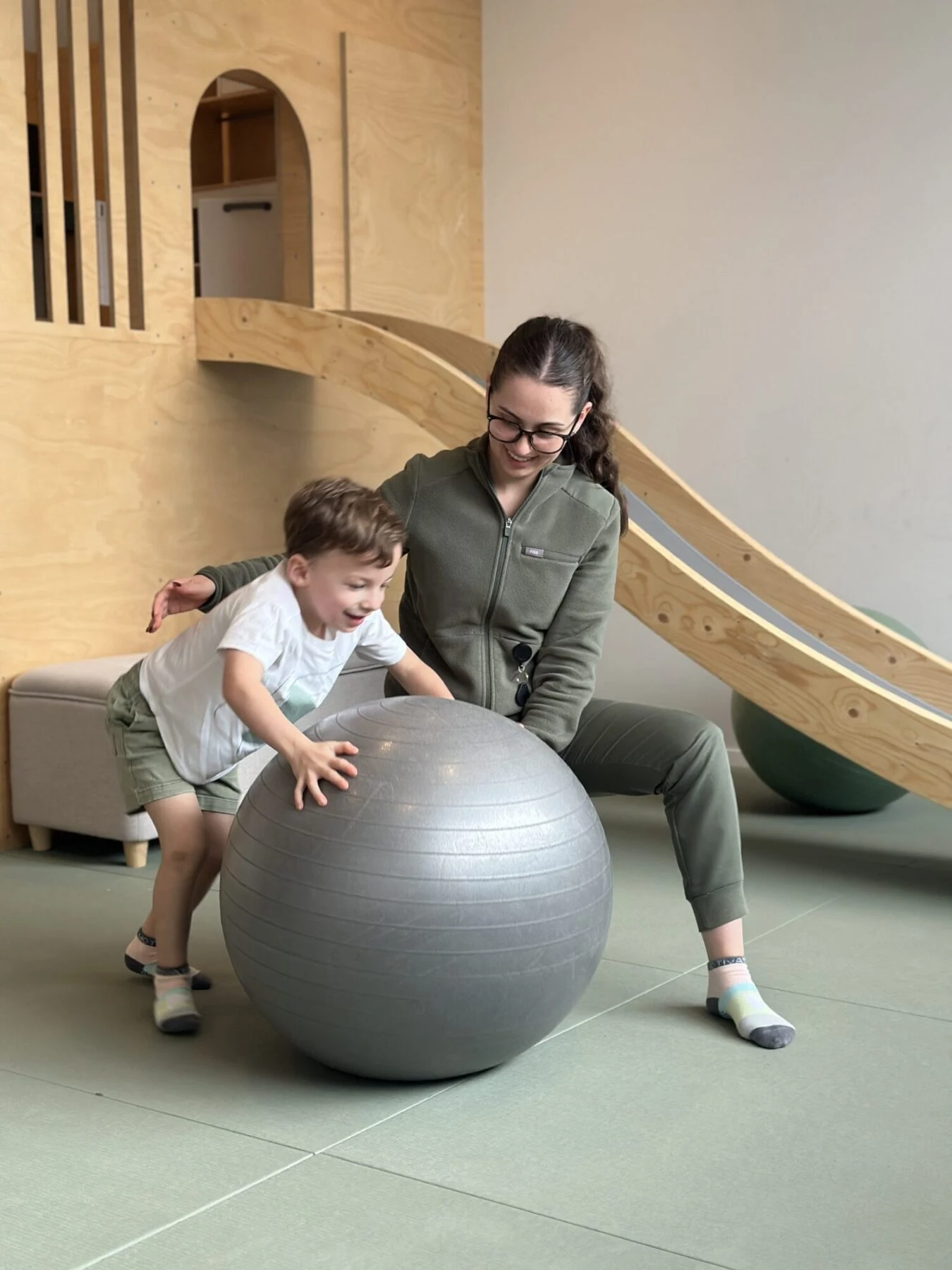 Occupational therapist supporting a child on an exercise ball