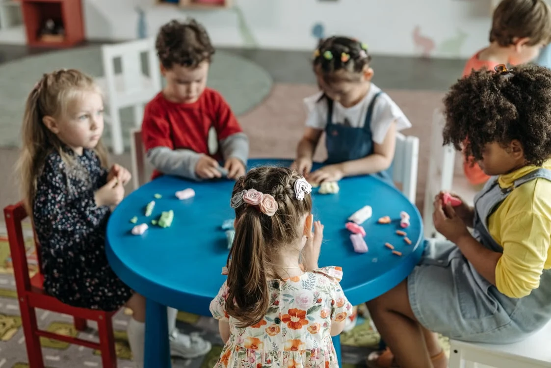A small group of children playing together at a table with a therapist
